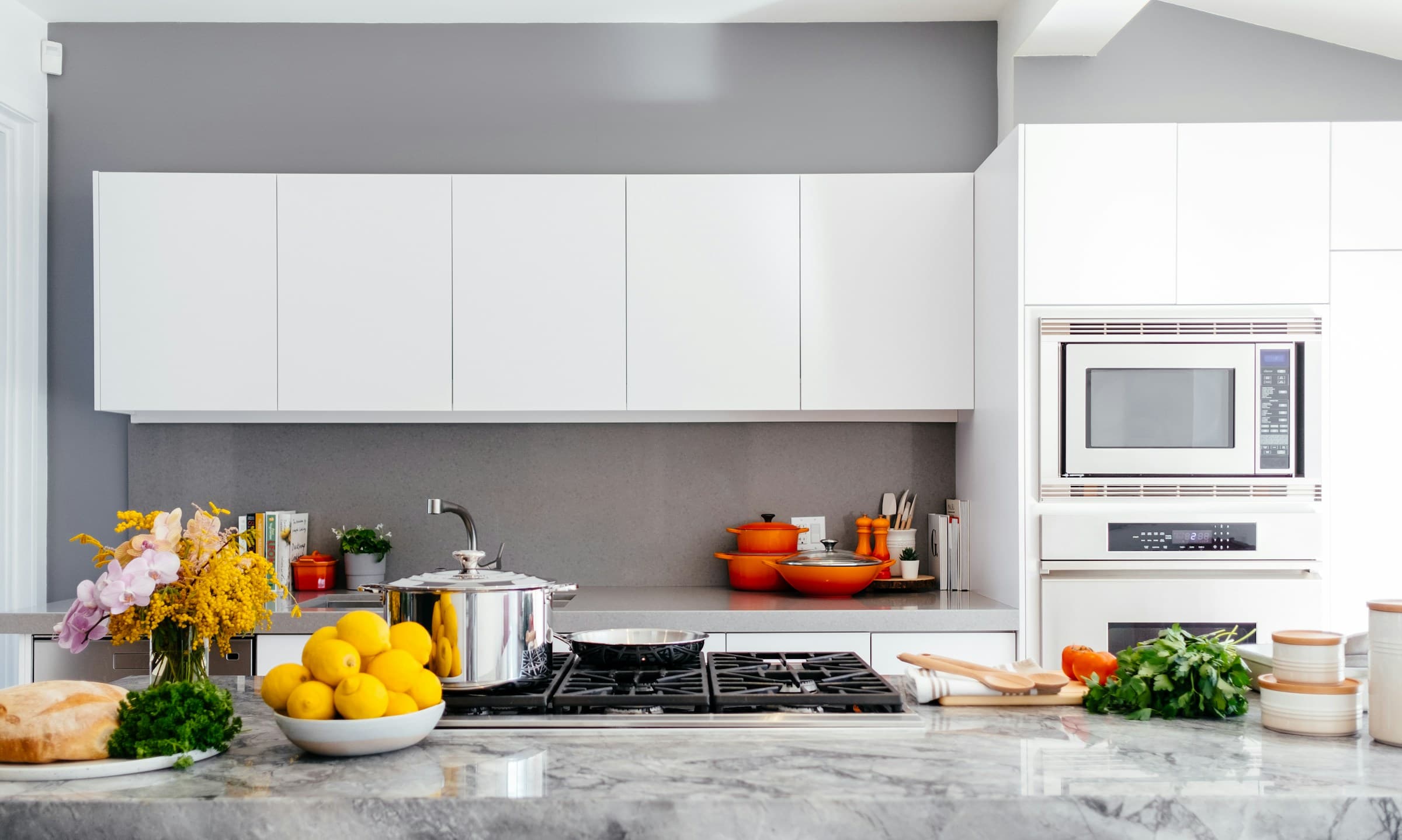 Bright modern kitchen with white cabinetry, wood accents and pendant lighting